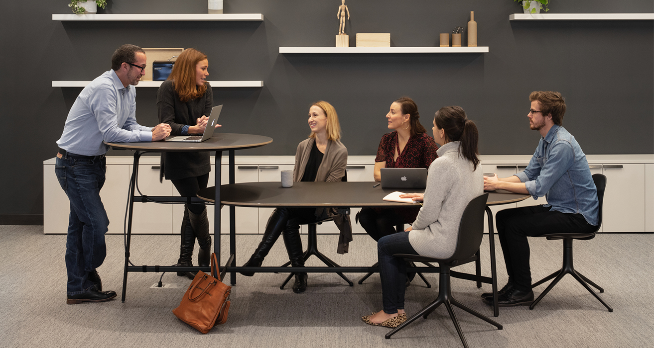 Image of colleagues chatting at multi-tiered desk