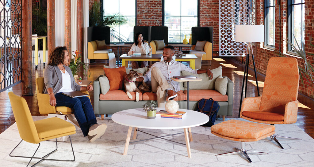 Image of lounge meeting area with colleagues chatting with dog on couch