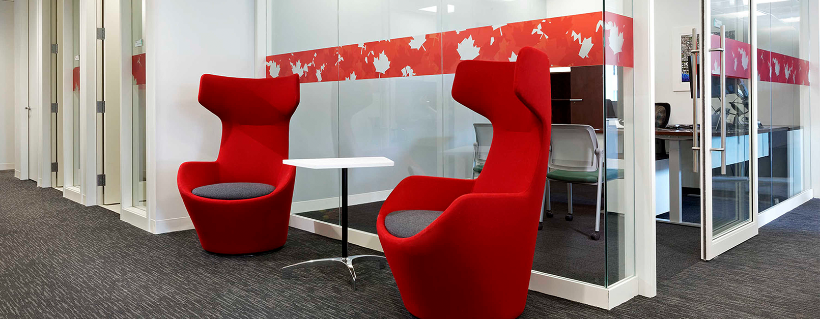 Two bright red accent chairs in front of meeting rooms