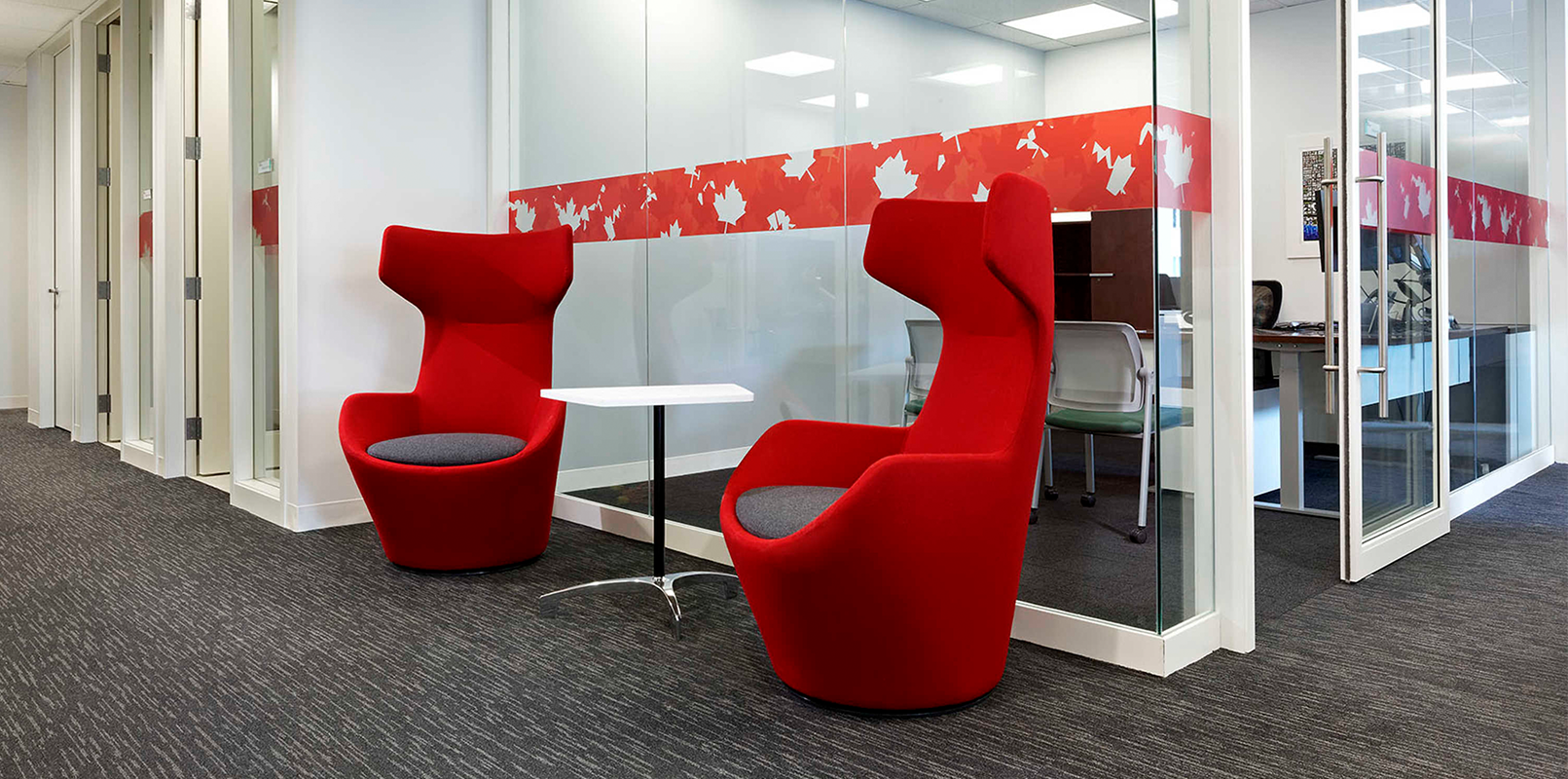 Two bright red accent chairs in front of meeting rooms