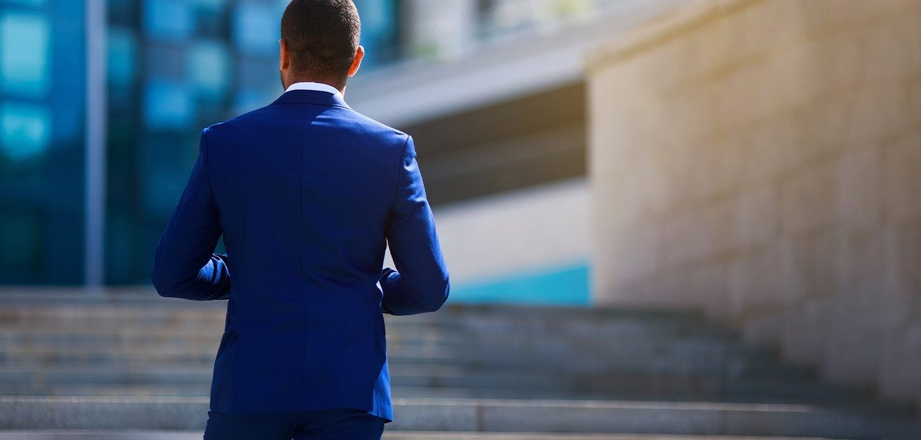 Man in blue suit facing office building stairs